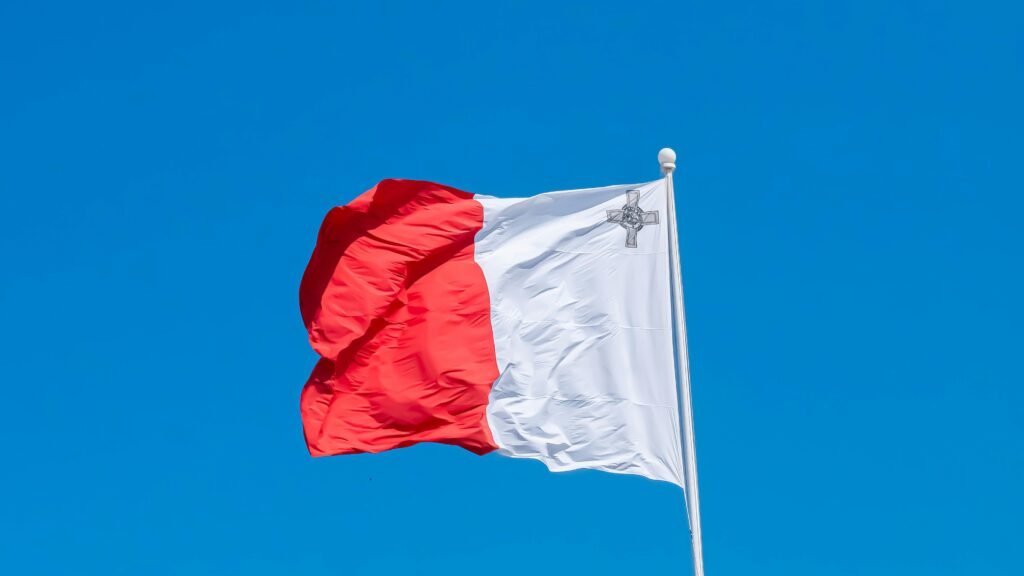 Vibrant image of the Maltese flag waving proudly against a clear blue sky, showcasing Malta's national pride.